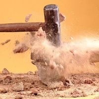 Sledgehammer breaking rocks. (demolishing, crushing, blurred motion)