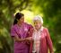 Happy young nurse assisting an elderly patient walking outside