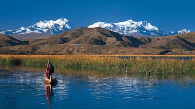 Aymara man poling a reed boat on Lake Titicaca