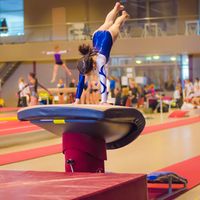 Young gymnast girl performing jump on a vault while practicing for the competition