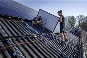 Op het dak van een stal van een boerderij worden zonnepanelen gelegd