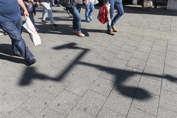 Mensen op straat lopen langs schaduw van beveiligingscamera