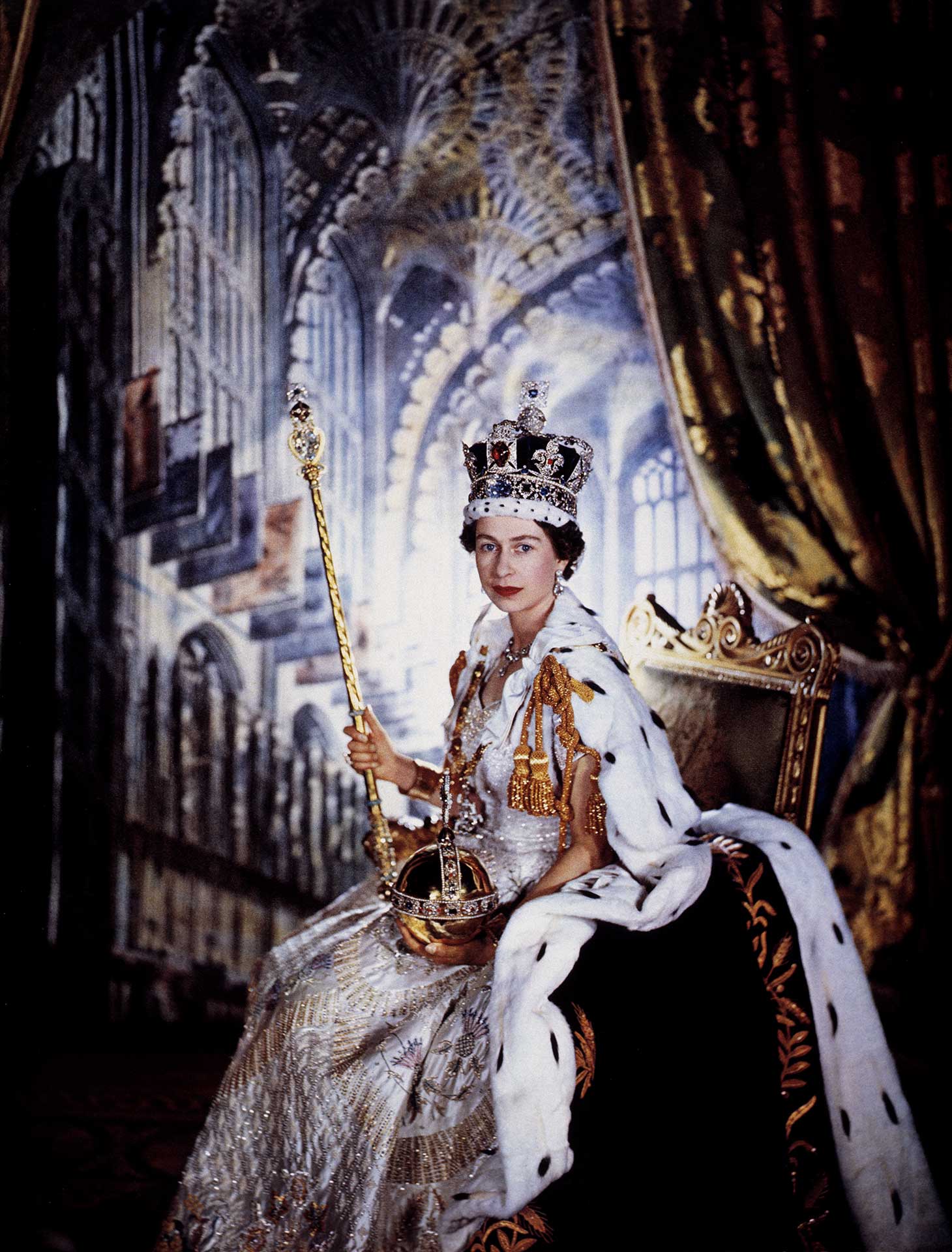 Queen Elizabeth II sitting with a backdrop of a vaulted cathedral. She wears a large crown and holds a golden sceptre and jewel encrusted, gold orb.