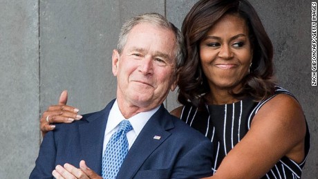 Former US President George W. Bush receives a hug from US First Lady Michelle Obama as they attend the opening ceremony for the Smithsonian National Museum of African American History and Culture on September 24, 2016 in Washington, D.C.  