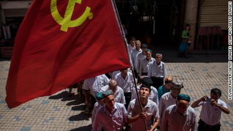 KASHGAR, CHINA - JUNE 30: Ethnic Uyghur members of the Communist Party of China carry a flag as they take part in an organized tour on June 30, 2017 in the old town of Kashgar, in the far western Xinjiang province, China. Kashgar has long been considered the cultural heart of Xinjiang for the province&#39;s nearly 10 million Muslim Uyghurs. At an historic crossroads linking China  to Asia, the Middle East, and Europe, the city has  changed under Chinese rule with government development, unofficial Han Chinese settlement to the western province, and restrictions imposed by the Communist Party. Beijing says it regards Kashgar&#39;s development as an improvement to the local economy, but many Uyghurs consider it a threat that is eroding their language, traditions, and cultural identity.  The friction has fuelled a separatist movement that has sometimes turned violent, triggering a crackdown on what China&#39;s government considers &#39;terrorist acts&#39; by religious extremists.  Tension has increased with stepped up security in the city and the enforcement of measures including restrictions at mosques. (Photo by Kevin Frayer/Getty Images)