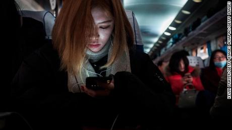 BEIJING, CHINA - JANUARY 25: A Chinese traveler rests as she holds her mobile phone on a crowded train between Beijing and Shijiazhuang, on January 25, 2017 in Hebei province, northern China. Millions of Chinese will travel home to visit families in what is often called the largest human migration during the Spring Festival holiday period that begins with the Lunar New Year on January 28, 2017.  (Photo by Kevin Frayer/Getty Images)