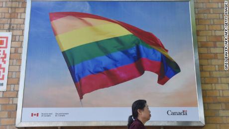 In this photo taken on May 18, 2018 a woman walks past a poster of a rainbow flag outside the Canadian embassy in Beijing. - China&#39;s LGBT community may not get much support from authorities, but in a sign of growing tolerance in Chinese society, people are using the power of hashtag campaigns to denounce attacks on gays and lesbians. (Photo by GREG BAKER / AFP)        (Photo credit should read GREG BAKER/AFP/Getty Images)