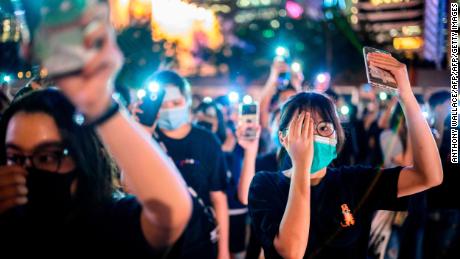 TOPSHOT - Secondary school students cover their right eye as they hold up their phone torches while attending a rally at Edinburgh Place in Hong Kong on August 22, 2019. - Hong Kong student leaders on Thursday announced a two-week boycott of lectures from the upcoming start of term, as they seek to keep protesters on the streets and pressure on the government. (Photo by Anthony WALLACE / AFP)        (Photo credit should read ANTHONY WALLACE/AFP/Getty Images)