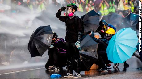 Pro-democracy protesters react as police fire water cannons outside the government headquarters in Hong Kong on September 15, 2019. - Hong Kong riot police fired tear gas and water cannons on September 15 at hardcore pro-democracy protesters hurling rocks and petrol bombs, in a return to the political chaos plaguing the city. (Photo by Isaac LAWRENCE / AFP) (Photo by ISAAC LAWRENCE/AFP via Getty Images)