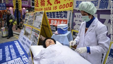 Falun Gong members perform a mock forced organ removal performance in a shopping district of Hong Kong on January 12, 2013. The Falun Gong, a quasi martial arts-religious movement, claim that their members have been persecuted through torture and intimidation, and frequently call to dissolve the Chinese Communist Party (CCP). The CCP claim the Falun Gong are a threat to social stability in China. AFP PHOTO / Antony DICKSON        (Photo credit should read ANTONY DICKSON/AFP via Getty Images)