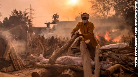 NEW DELHI, INDIA - MAY 01: A priest who works at a crematorium performs the last rites of a patient who died of COVID-19 amid burning funeral pyres on May 01, 2021 in New Delhi, India. With cases crossing 400,000 a day and with more than 3500 deaths recorded in the last 24 hours, India&#39;s Covid-19 crisis is intensifying and shows no signs of easing pressure on the country. A new wave of the pandemic has totally overwhelmed the country&#39;s healthcare services and has caused crematoriums to operate day and night as the number of victims continues to spiral out of control. (Photo by Anindito Mukherjee/Getty Images)