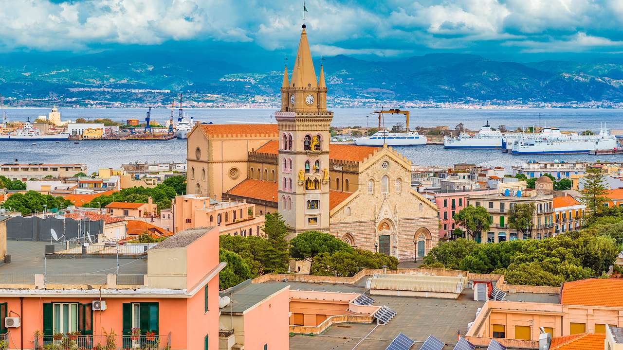 An aerial view of a historical town with trees and a cathedral next to a coastline