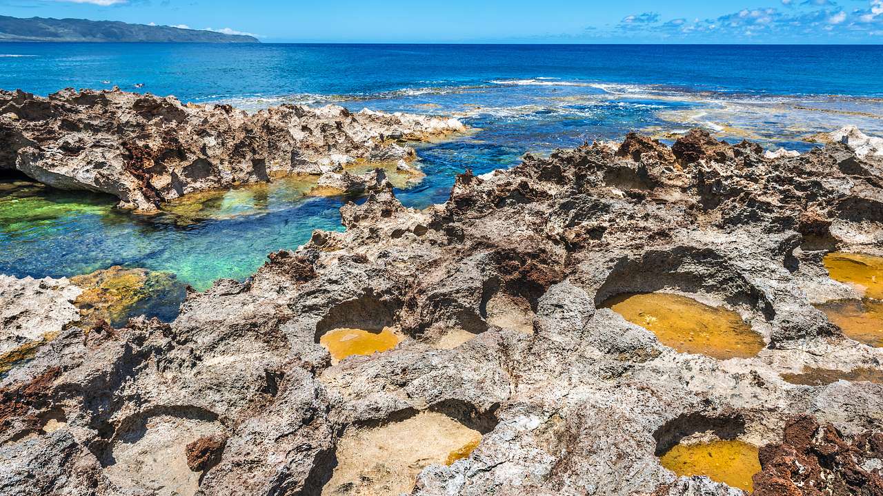 Scenic view of a beach with waves breaking against a rocky shore on a beautiful day