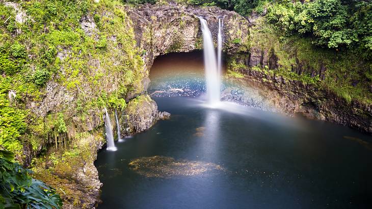 Top view over a lagoon below a waterfall forming a colorful rainbow