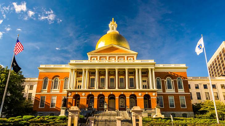 Sun shining on a gold dome building top with a fence in front