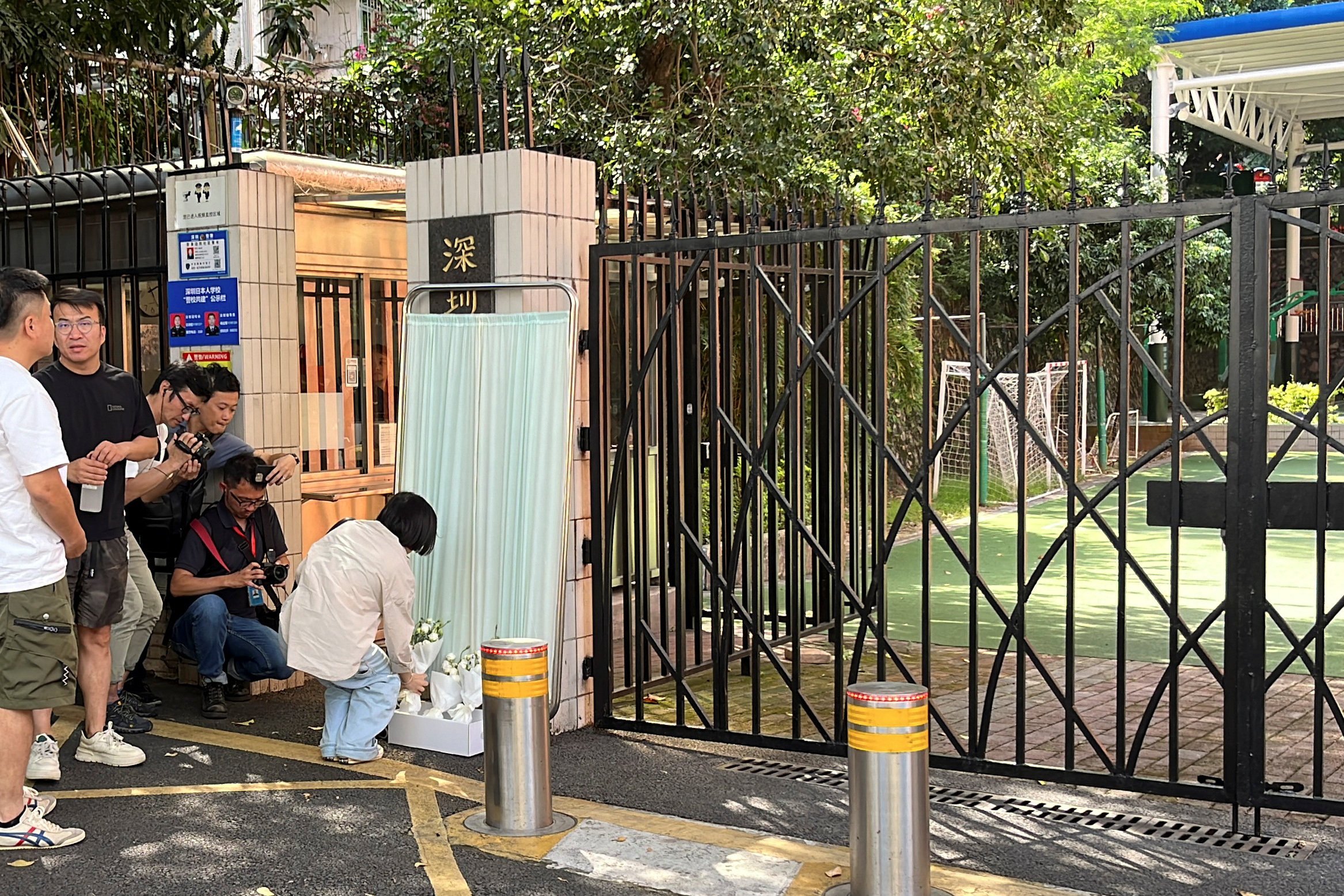 A woman lays a bouquet of flowers outside Shenzhen Japanese School on September 19, following the death of a 10-year-old child who was stabbed on the way to the school. Photo: Reuters 