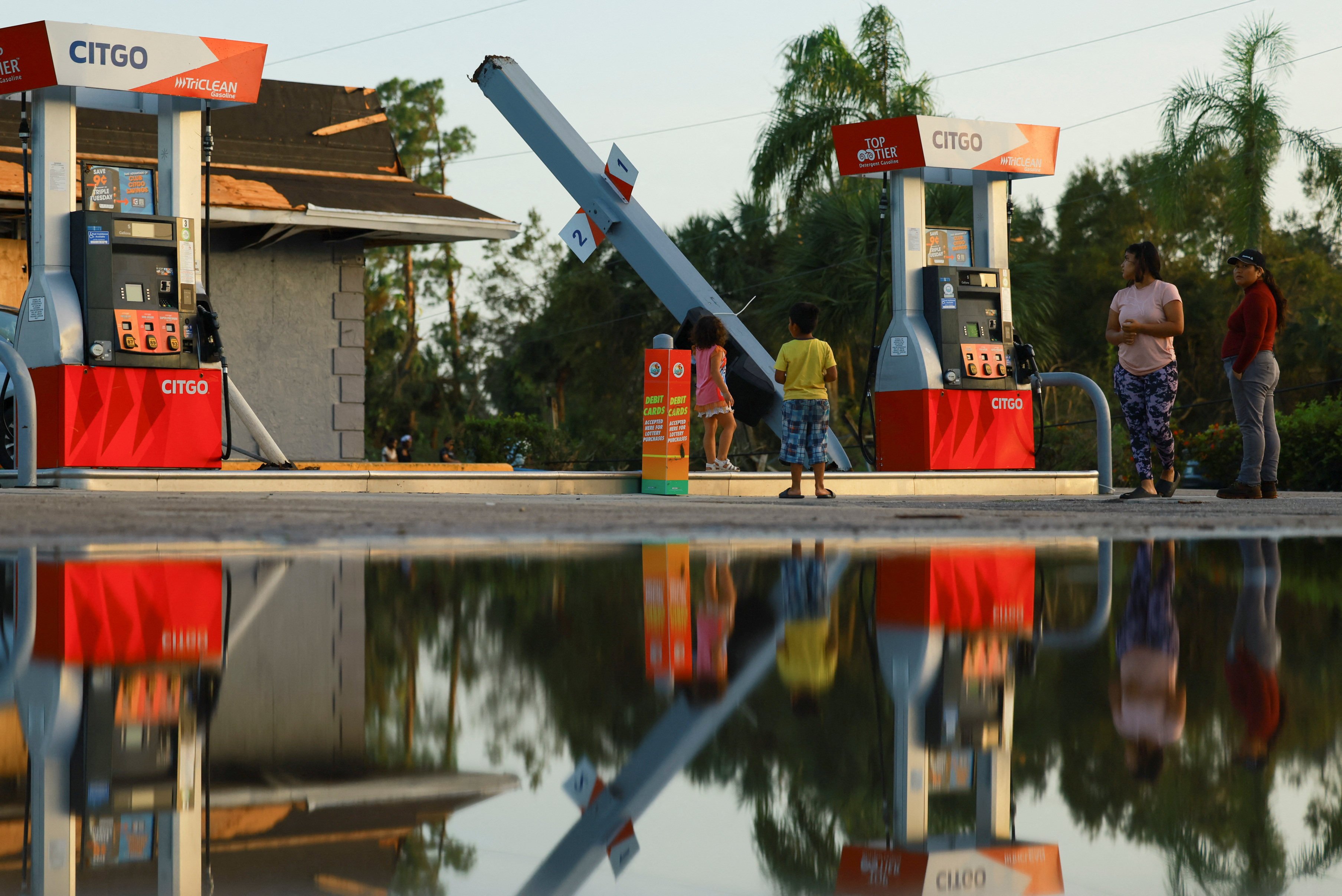 People stand near a bent structure at a gas station, after Hurricane Milton made landfall, in Lakewood Park, near Fort Pierce. Photo: Reuters