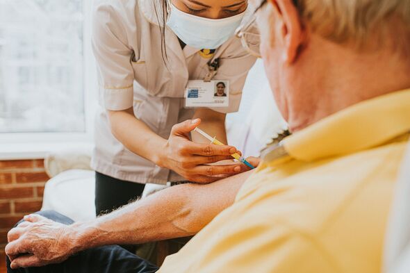 Female Nurse gives an Elderly man an injection in his arm