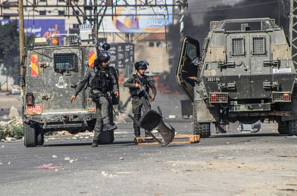 Israeli soldiers kick rubble off the ground placed by...