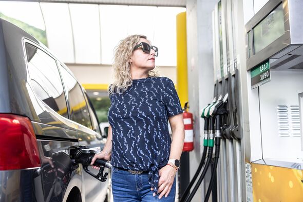 A female driver fills diesel fuel in her car and checks the amount filled at the gas station.