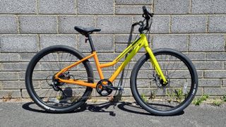 A pack shot of a bright yellow and orange bicycle with a step through frame