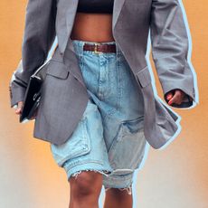 a woman walking in street style wearing a pair of baggy jorts