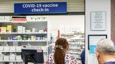 People stand in line at a Walgreens pharmacy counter offering Covid-19 vaccines.