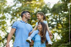 Smiling parents with a little girl on her mum's shoulders