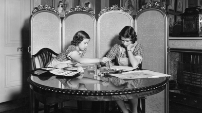 Princess Margaret Rose (1930 - 2002) and Princess Elizabeth (right) working on paintings in the school room of Buckingham Palace