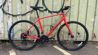 A Trek FX Disc hybrid in Viper Red against a wall