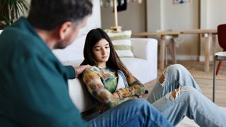 teenage girl sat against white sofa with man