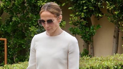 Jennifer Lopez wearing a white scalloped hem dress with a birkin bag and heels