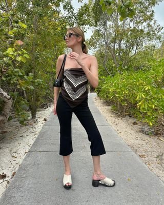 Woman in scarf top, black capris, and white clogs