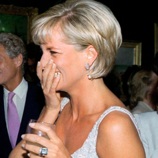 Princess Diana wearing a sleeveless dress covering her mouth and laughing