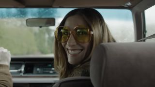 Sarah Levy's character smiling eerily into the camera inside a car in The Monkey