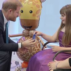 Prince Harry receiving a gift from Scarlett Cripps at WellChild Awards