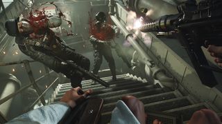 Wolfenstein 2 screenshot of the player character shooting two enemies on a flight of stairs as blood spurts from their wounds