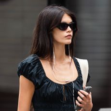 Kaia Gerber walks around lower Manhattan in an all black summer outfit including a dress and a delicate necklace