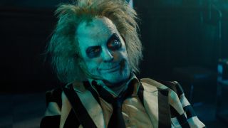 Michael Keaton sits with a grin of mild annoyance in Beetlejuice Beetlejuice.