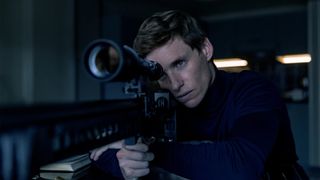 Eddie Redmayne preparing to take a shot with a sniper rifle in The Day of the Jackal.