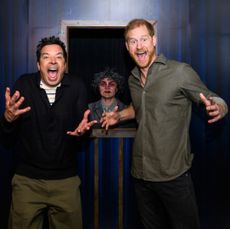 Prince Harry and Jimmy Fallon screaming in a haunted house with a creepy character behind them