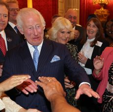 King Charles wearing a suit and dancing with a group of guests at Buckingham Palace