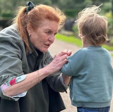 Sarah Ferguson wearing a green jacket kneeling down on a garden path talking to Ernest Brooksbank