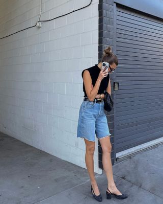 Woman talking on the phone wearing jean shorts, slingbacks, and a black top