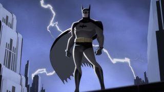 An animated batman stands atop of a rooftop with lightening behind him