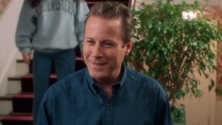 John Heard stands smiling while in conversation in his house in Home Alone.