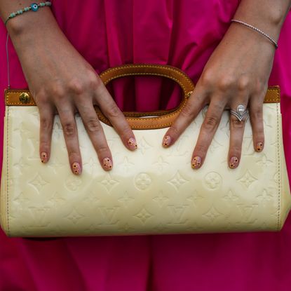 painted nails holding yellow louis vuitton bag 