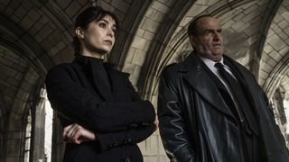 Sofia Falcone and Oz Cobb standing in a cemetery building in The Penguin