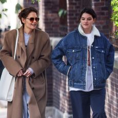 Katie Holmes and Suri Cruise walk in Manhattan where Katie Holmes wears a camel coat and Suri Cruise wears a denim trucker jacket with fleece lining