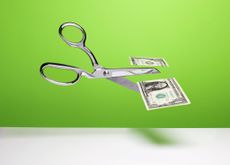 Stainless steel scissors in mid air cutting a US $1 dollar bill over white surface, gradated green background.